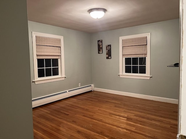 unfurnished room with a baseboard heating unit and dark hardwood / wood-style flooring