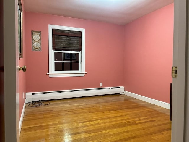 unfurnished room featuring a baseboard heating unit and light wood-type flooring