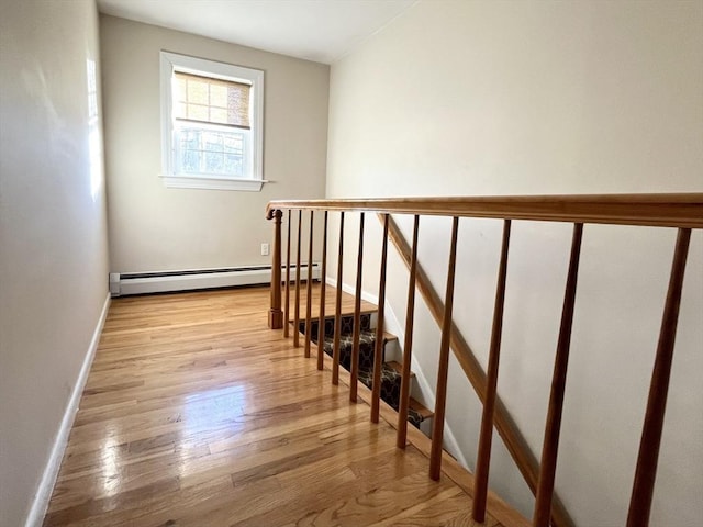 stairway featuring a baseboard heating unit and hardwood / wood-style flooring