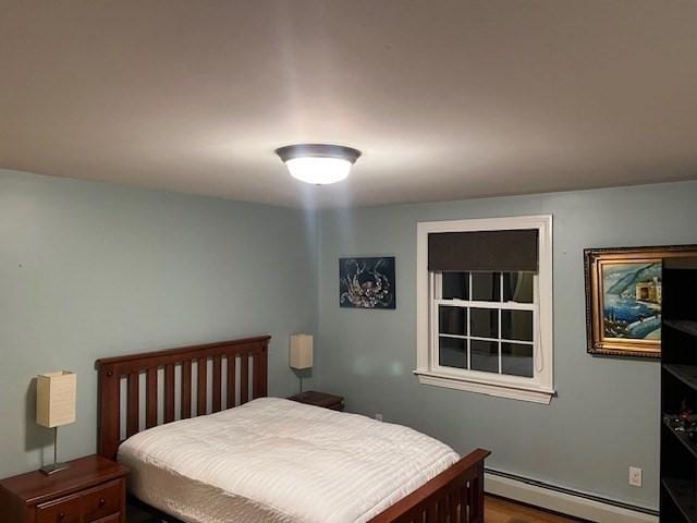 bedroom with a baseboard radiator and hardwood / wood-style floors