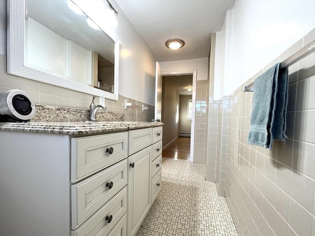 bathroom with tile walls, vanity, tile patterned flooring, and a baseboard heating unit