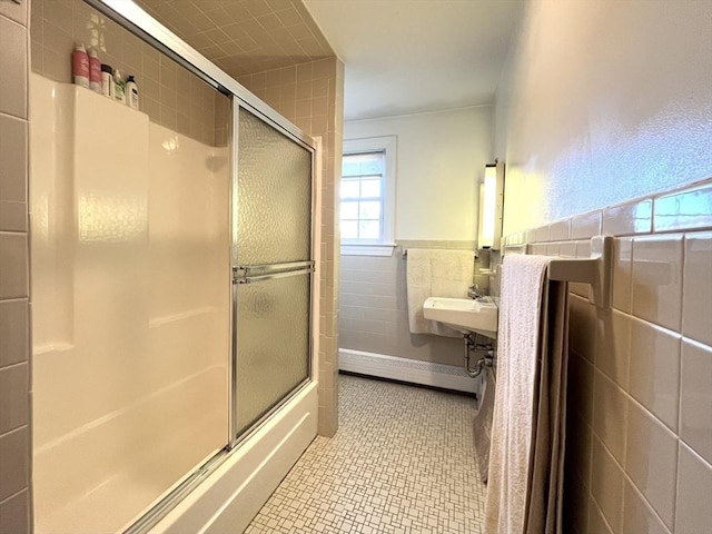 bathroom featuring bath / shower combo with glass door, sink, tile walls, and tile patterned floors