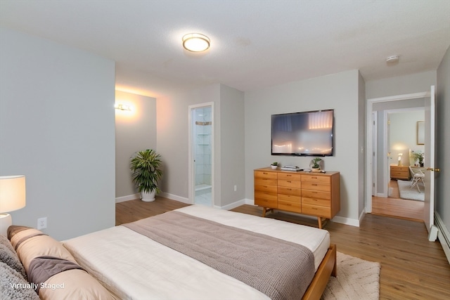 bedroom featuring hardwood / wood-style floors, ensuite bathroom, and baseboard heating