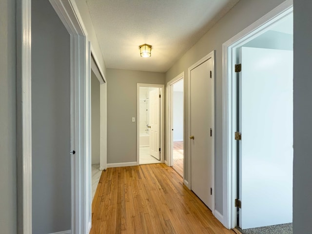 corridor featuring light hardwood / wood-style floors and a textured ceiling