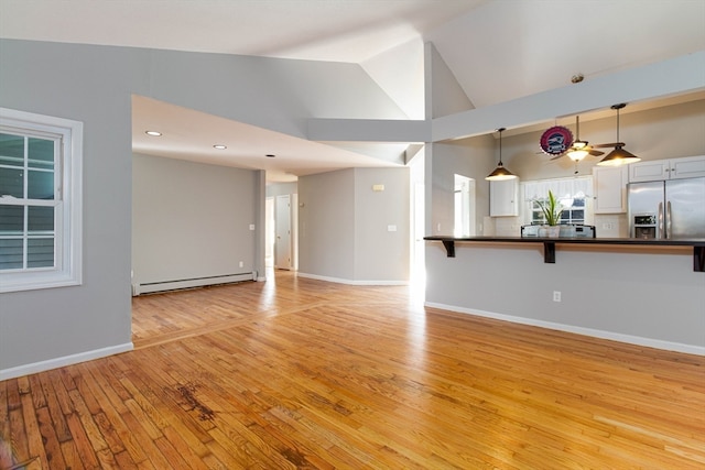 unfurnished living room with ceiling fan, light hardwood / wood-style flooring, lofted ceiling, and a baseboard heating unit