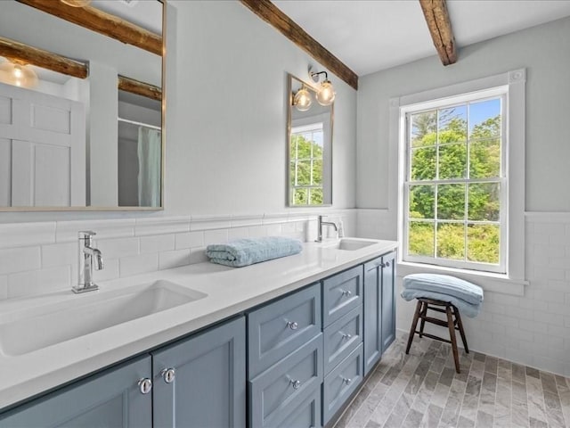 131 Cedar St, Middleboro, MA 02346 - bathroom with beamed ceiling, double vanity, tile walls, and a wainscoted wall