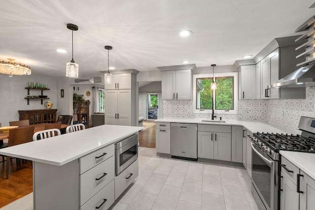 kitchen featuring appliances with stainless steel finishes, gray cabinetry, a sink, tasteful backsplash, and a breakfast bar