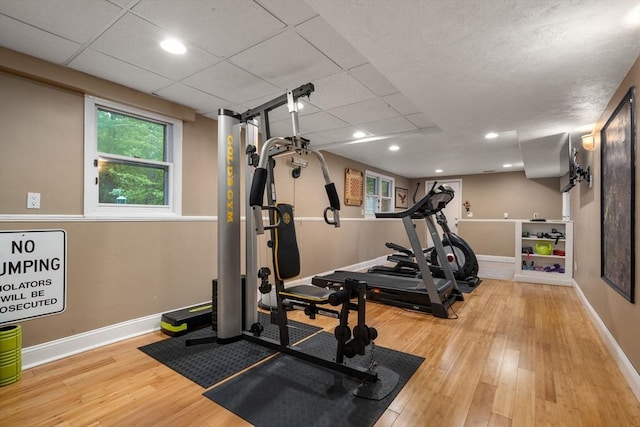 workout room featuring wood finished floors, baseboards, and a paneled ceiling