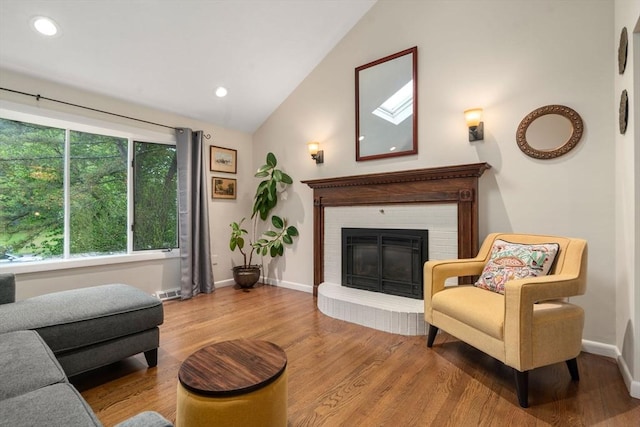 living room with lofted ceiling, wood finished floors, a brick fireplace, baseboards, and recessed lighting