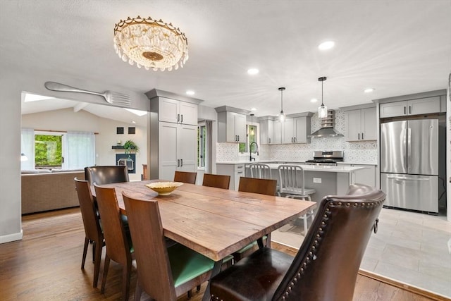 dining room with lofted ceiling, light wood-style floors, and recessed lighting