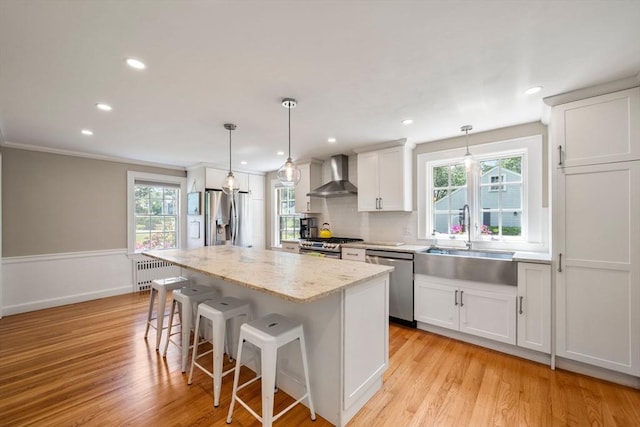 38 Fairmount Rd, Reading, MA 01867 - kitchen featuring appliances with stainless steel finishes, wall chimney exhaust hood, radiator heating unit, light wood-type flooring, and recessed lighting