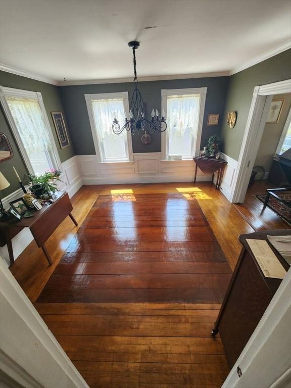 dining area with a chandelier, wainscoting, and hardwood / wood-style flooring