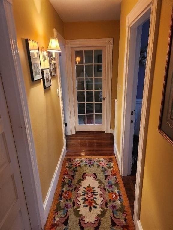 corridor featuring wood finished floors and baseboards