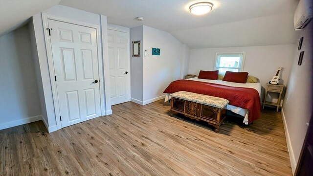 3 Bennett St, Hudson, MA 01749 - bedroom with a wall mounted air conditioner, light wood-type flooring, vaulted ceiling, and baseboards