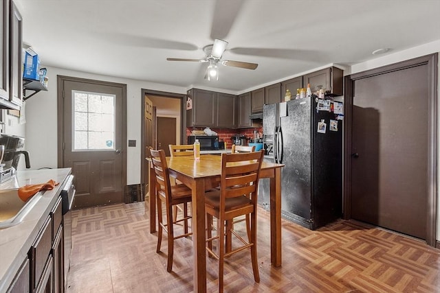 kitchen with light parquet floors, black appliances, ceiling fan, tasteful backsplash, and dark brown cabinets