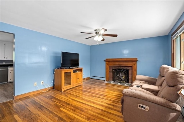 9 Lillian Rd, Acton, MA 01720 - living room featuring baseboard heating, wood finished floors, a ceiling fan, a brick fireplace, and baseboards