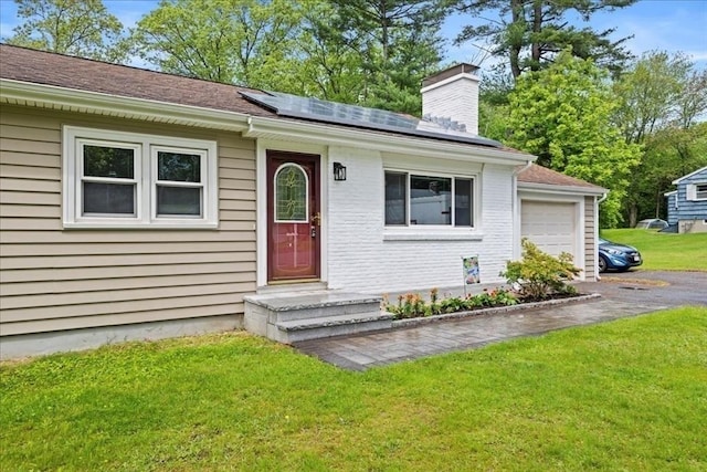 9 Lillian Rd, Acton, MA 01720 - view of front facade featuring roof mounted solar panels, a chimney, a front lawn, brick siding, and driveway