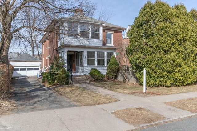 american foursquare style home with brick siding, a chimney, a detached garage, and an outdoor structure