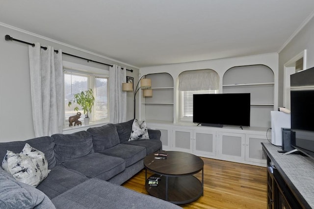 living room with light hardwood / wood-style floors, built in shelves, and ornamental molding