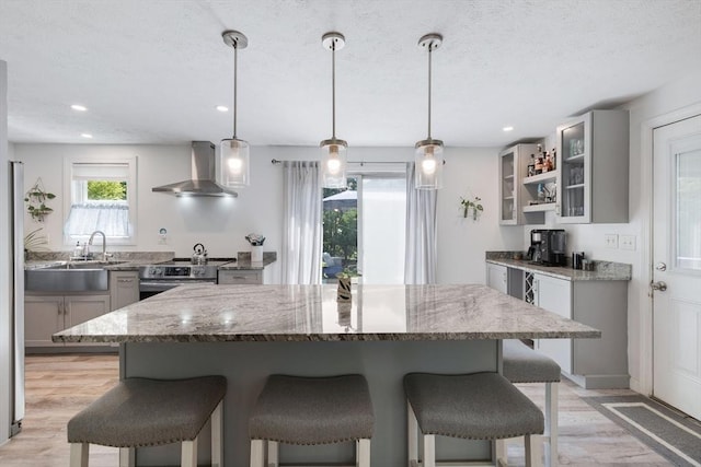853 Sandwich, Falmouth, MA 02536 - kitchen with wall chimney range hood, stainless steel electric range oven, gray cabinetry, a kitchen bar, and a sink