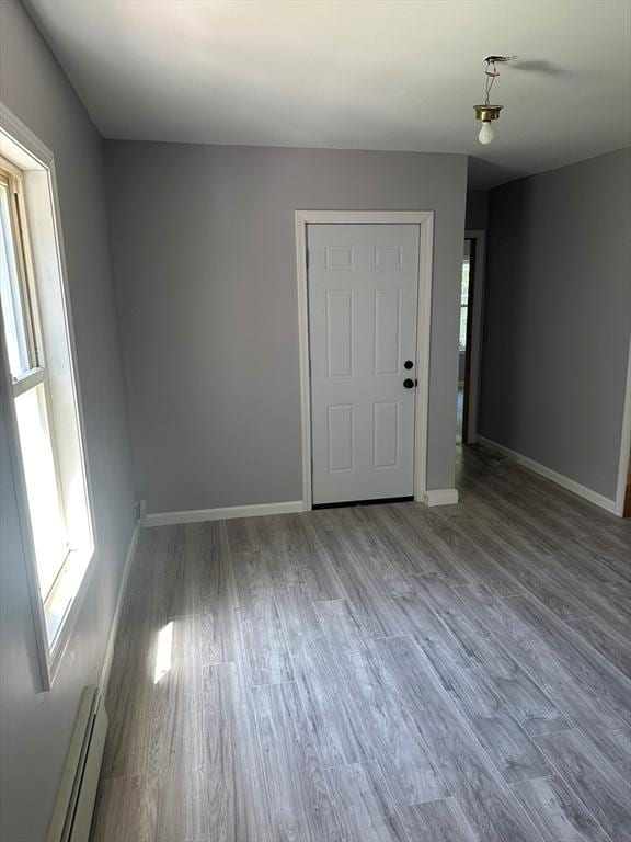 spare room featuring a baseboard heating unit and hardwood / wood-style floors