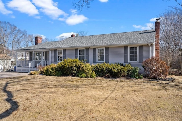 ranch-style house featuring a porch, a front yard, roof with shingles, and a chimney