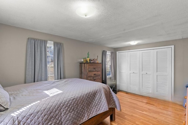 bedroom with light wood-style floors, a closet, and a textured ceiling