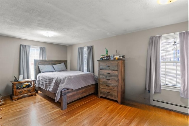 bedroom featuring a baseboard radiator, a textured ceiling, and light wood finished floors