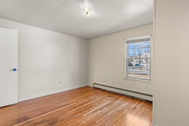 unfurnished room featuring a baseboard heating unit and hardwood / wood-style floors