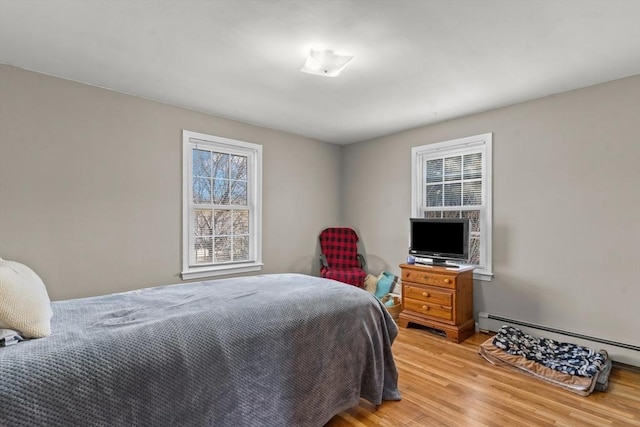 bedroom with a baseboard heating unit and light wood-type flooring