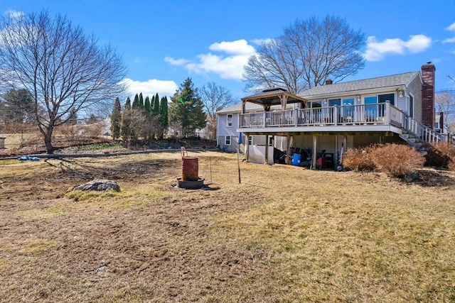 back of property with a lawn, a gazebo, stairway, a wooden deck, and a chimney