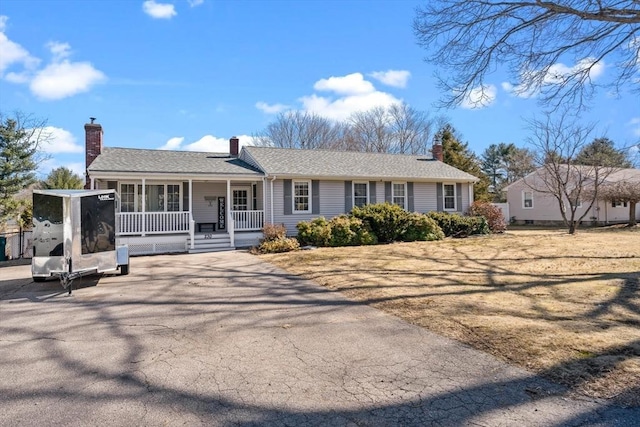 ranch-style home with a shingled roof, a porch, and a chimney