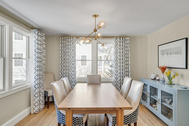 dining space with an inviting chandelier, a wealth of natural light, and light wood-type flooring