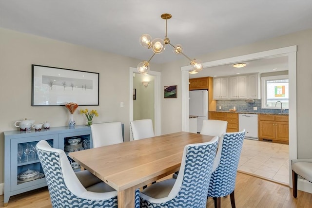 dining space featuring sink, a chandelier, and light hardwood / wood-style floors