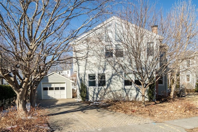 front facade featuring a garage and an outbuilding