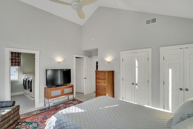 bedroom featuring multiple closets, washing machine and clothes dryer, ceiling fan, and high vaulted ceiling