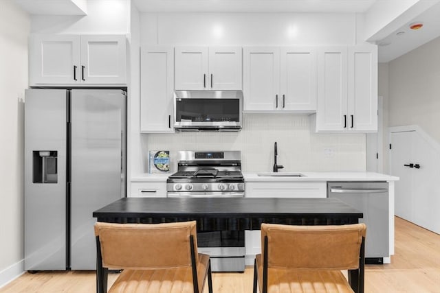 kitchen with backsplash, sink, white cabinets, and stainless steel appliances