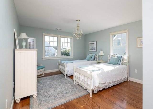 bedroom with multiple windows, an inviting chandelier, and dark hardwood / wood-style flooring