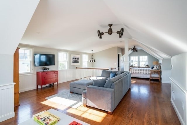 living room featuring decorative columns, dark wood-type flooring, a healthy amount of sunlight, and lofted ceiling