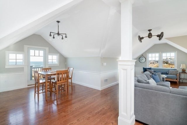 dining room featuring hardwood / wood-style floors, vaulted ceiling, and ornate columns