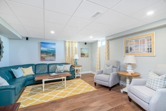 living room featuring hardwood / wood-style floors and a drop ceiling