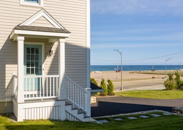 property entrance with a beach view, a yard, and a water view