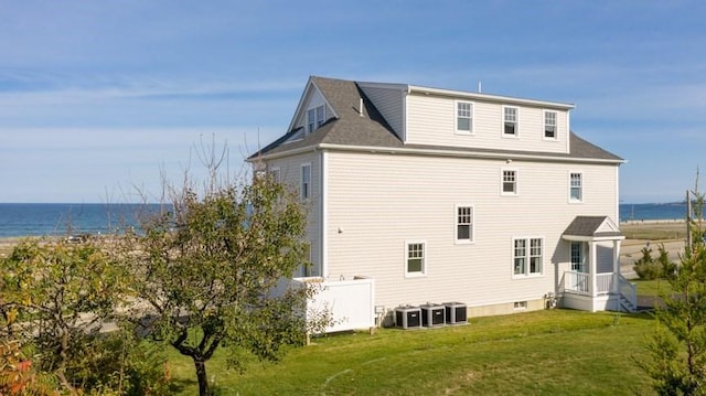 back of house featuring central AC unit, a lawn, and a water view