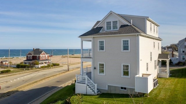 rear view of house featuring a yard and a water view