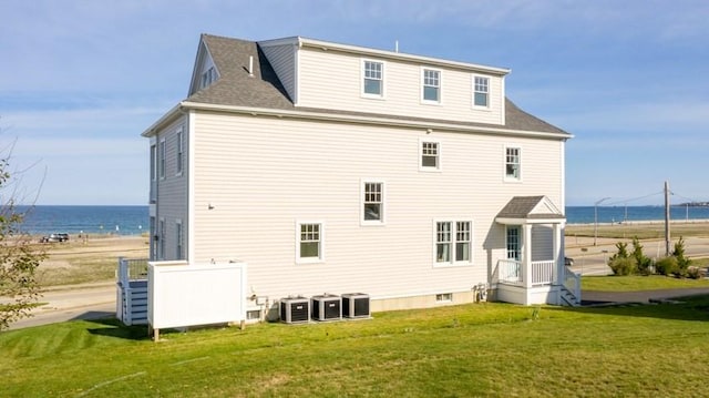 rear view of property featuring a lawn, a water view, and central AC