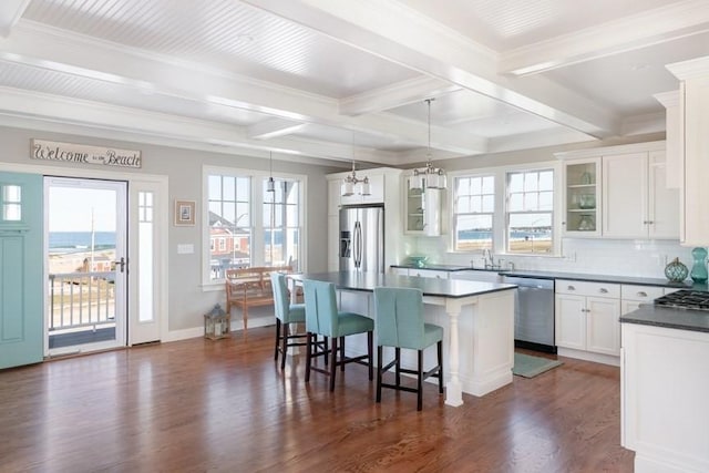 kitchen with pendant lighting, a center island, white cabinetry, stainless steel appliances, and a kitchen breakfast bar