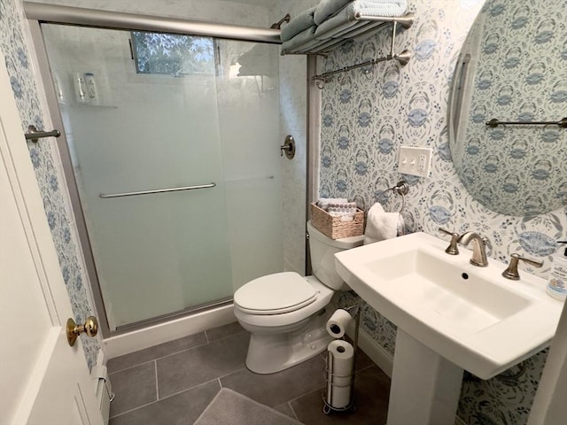 bathroom featuring a stall shower, toilet, tile patterned flooring, wallpapered walls, and a sink