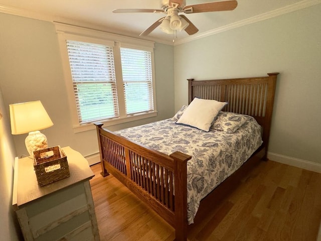 bedroom with wood finished floors, crown molding, baseboards, and ceiling fan