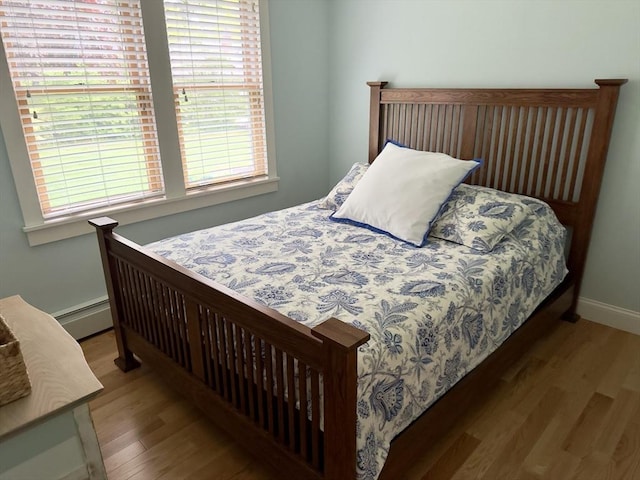 bedroom featuring wood finished floors, baseboards, and baseboard heating