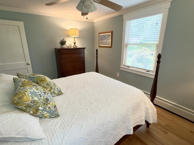 bedroom with wood finished floors, ornamental molding, ceiling fan, and a baseboard heating unit